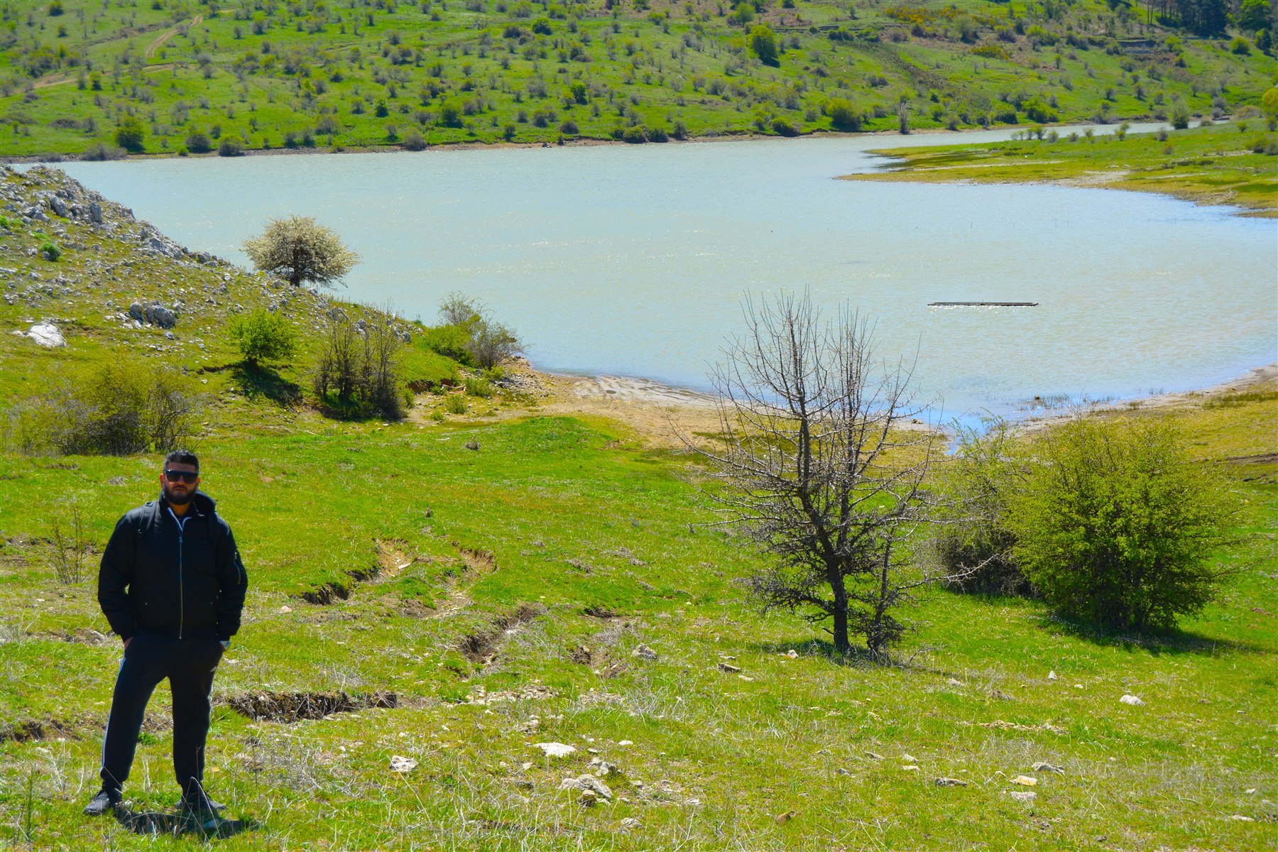 Mike beside a lake in a green mountain landscape