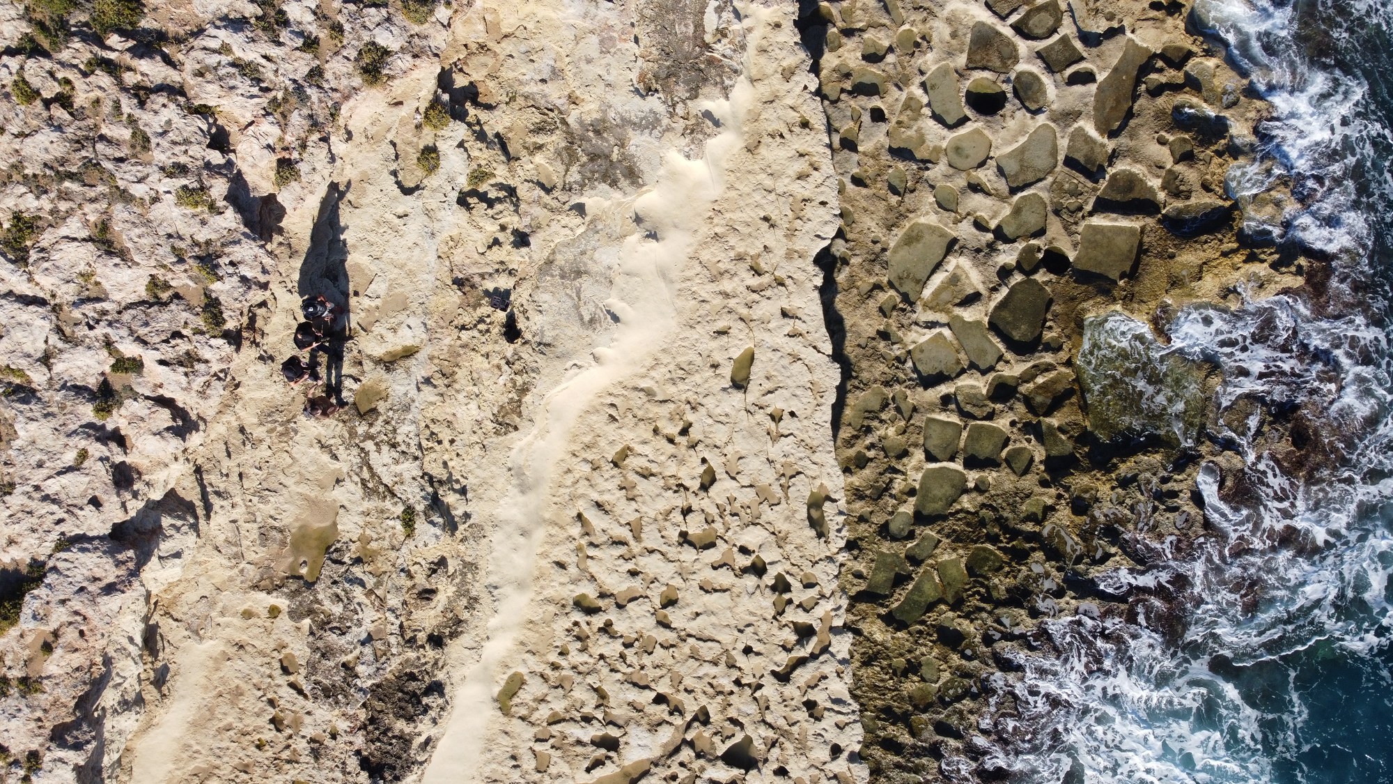 Top-down view of natural rock pools beside the open sea