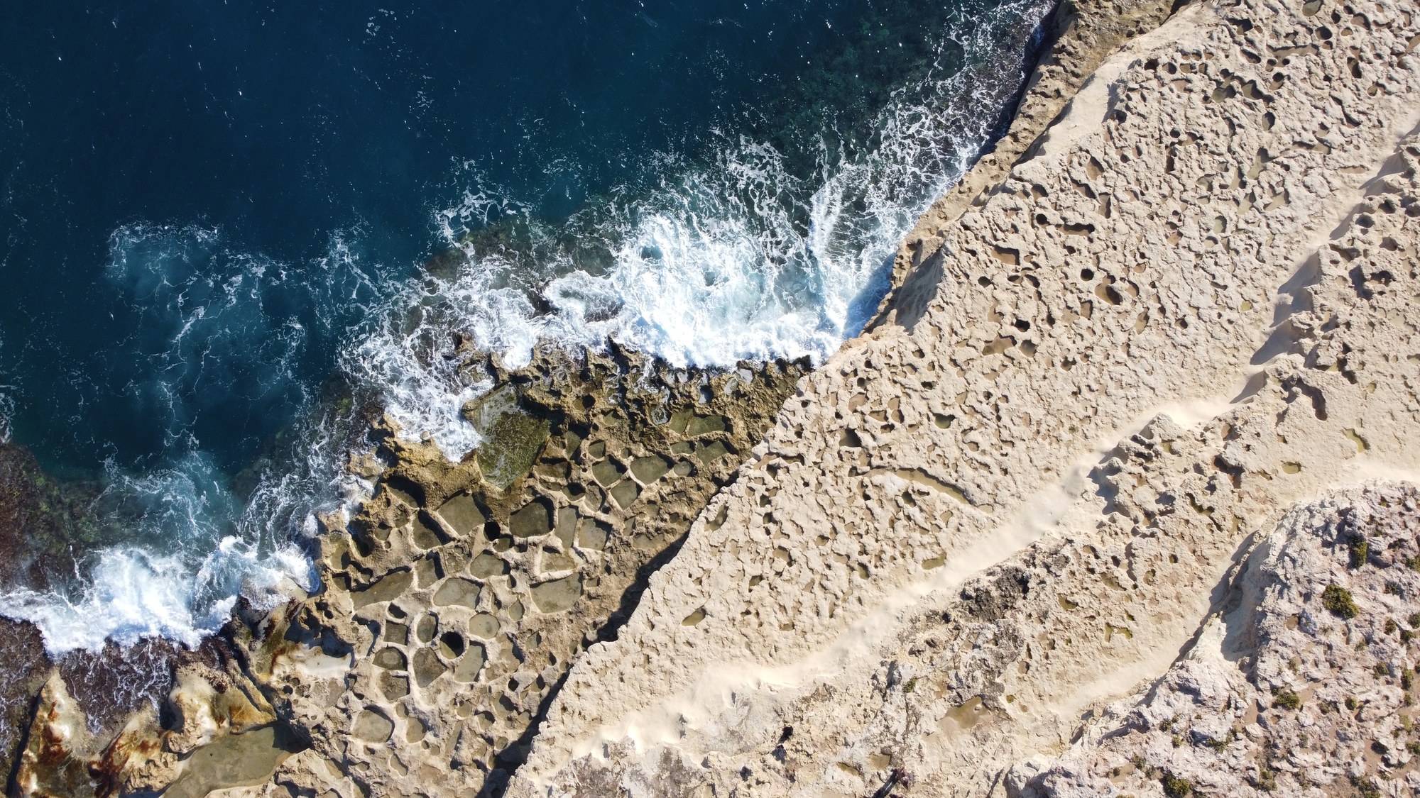 Waves breaking across the honeycombed limestone edge of Malta