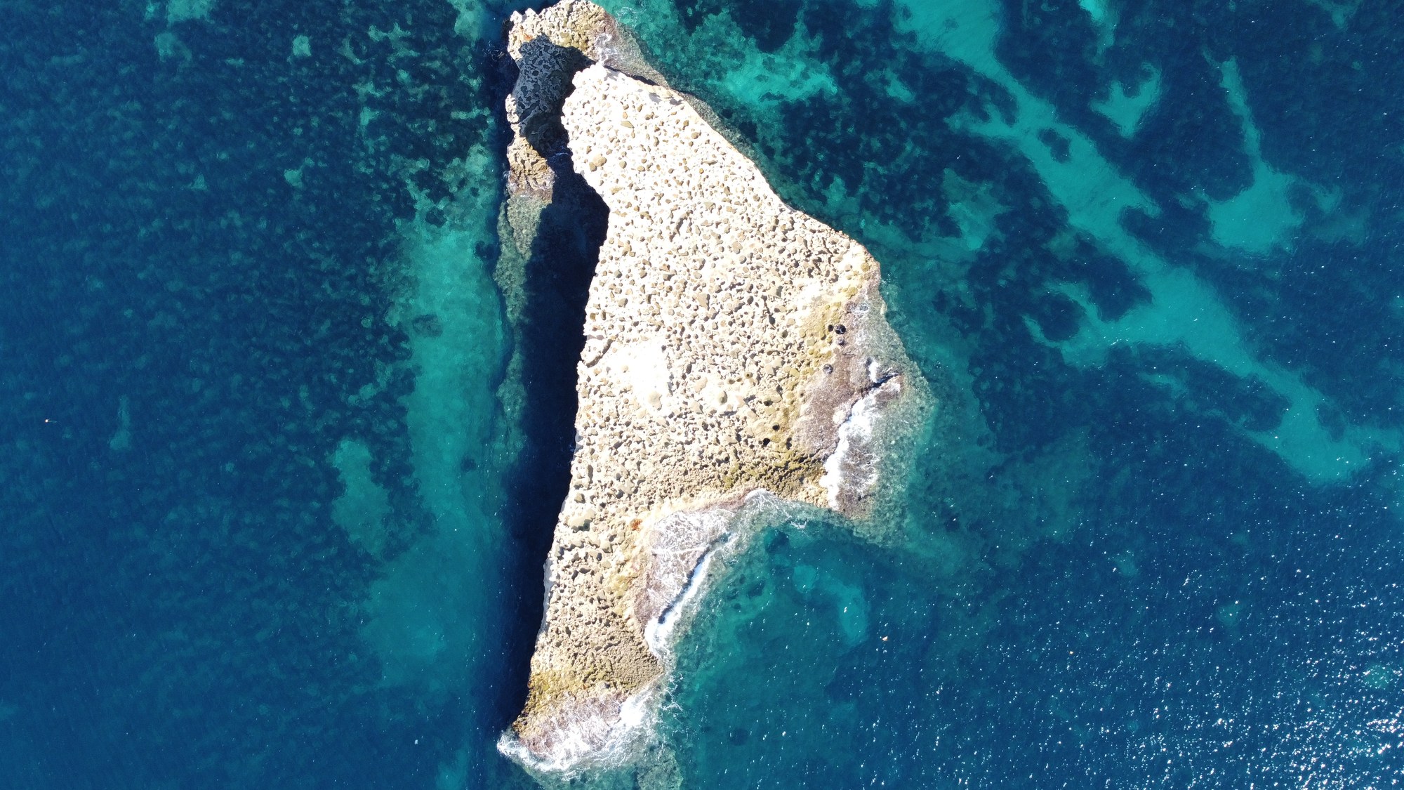 A small limestone islet surrounded by turquoise Mediterranean water