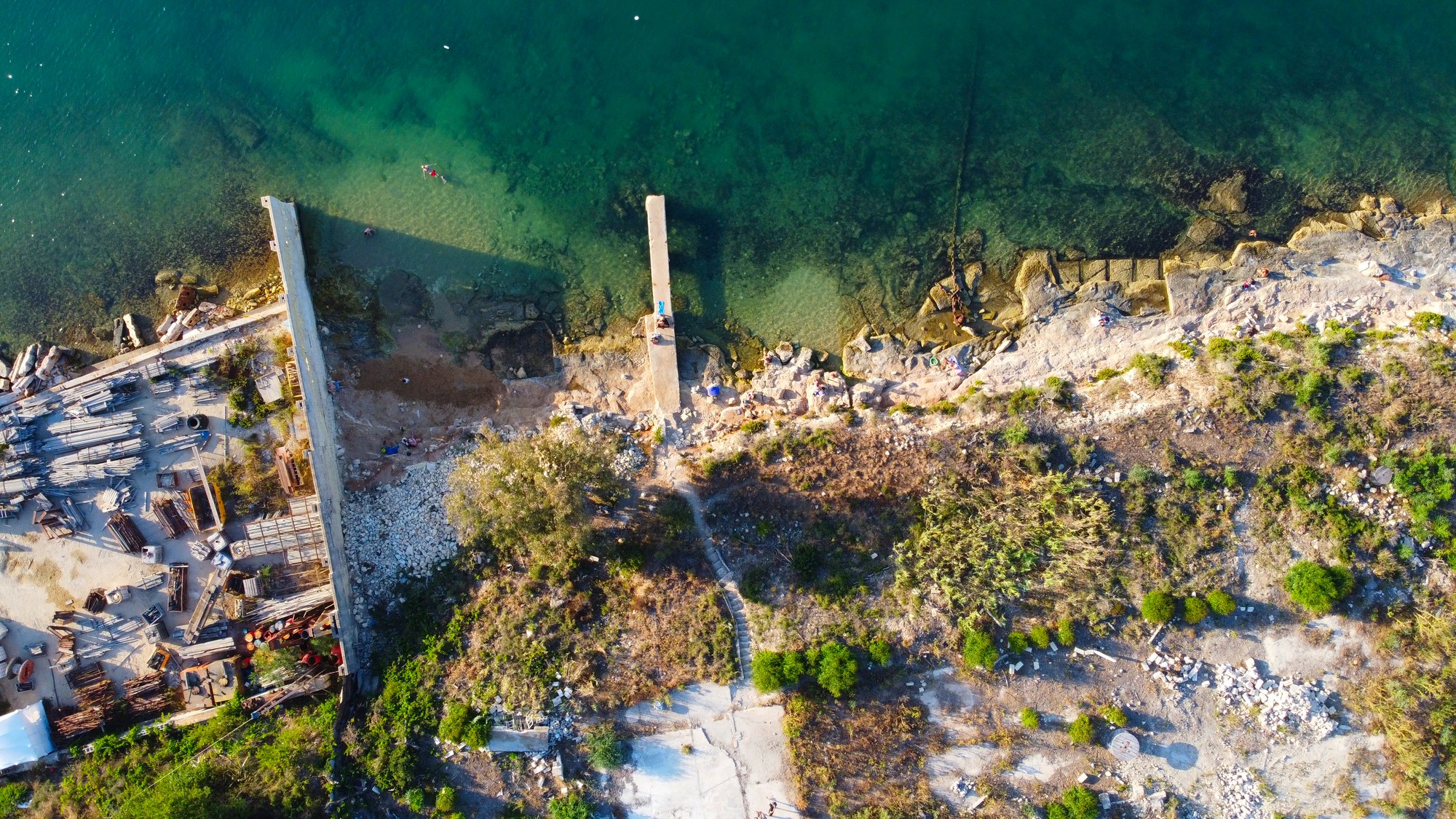 Top-down aerial view of a rugged Maltese shoreline and clear water