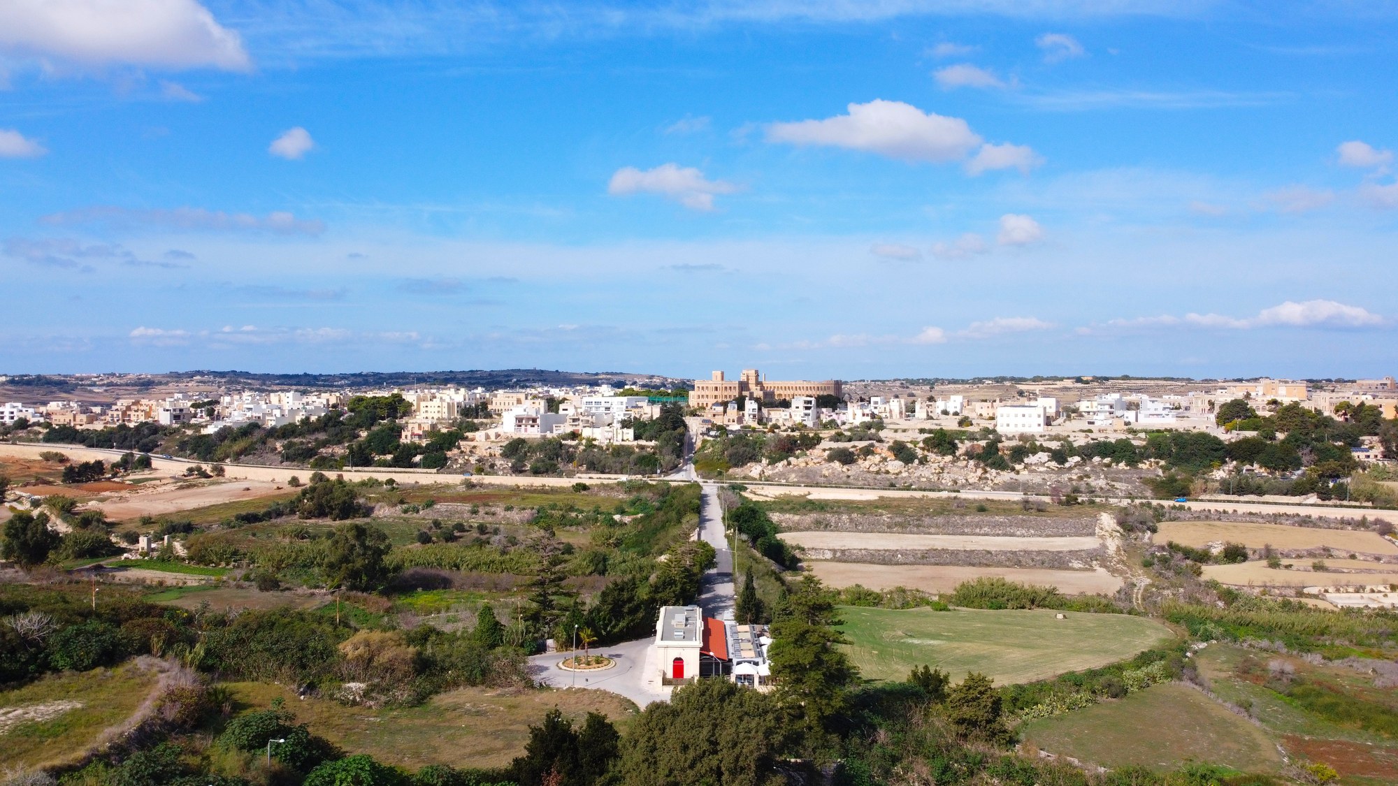 Aerial panorama of fields and countryside at the edge of a Maltese village