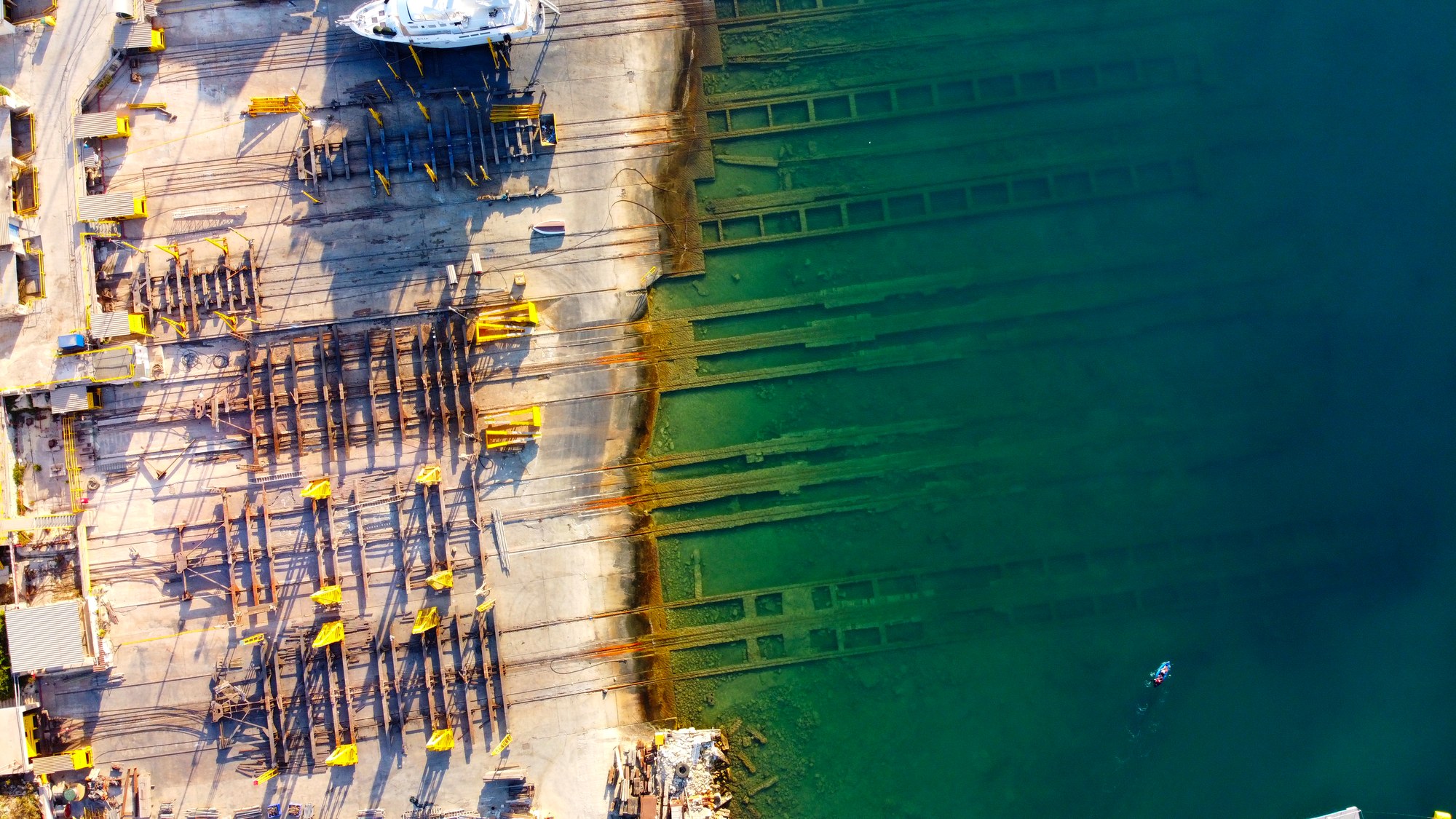 Top-down aerial view of a Maltese shipyard beside green water