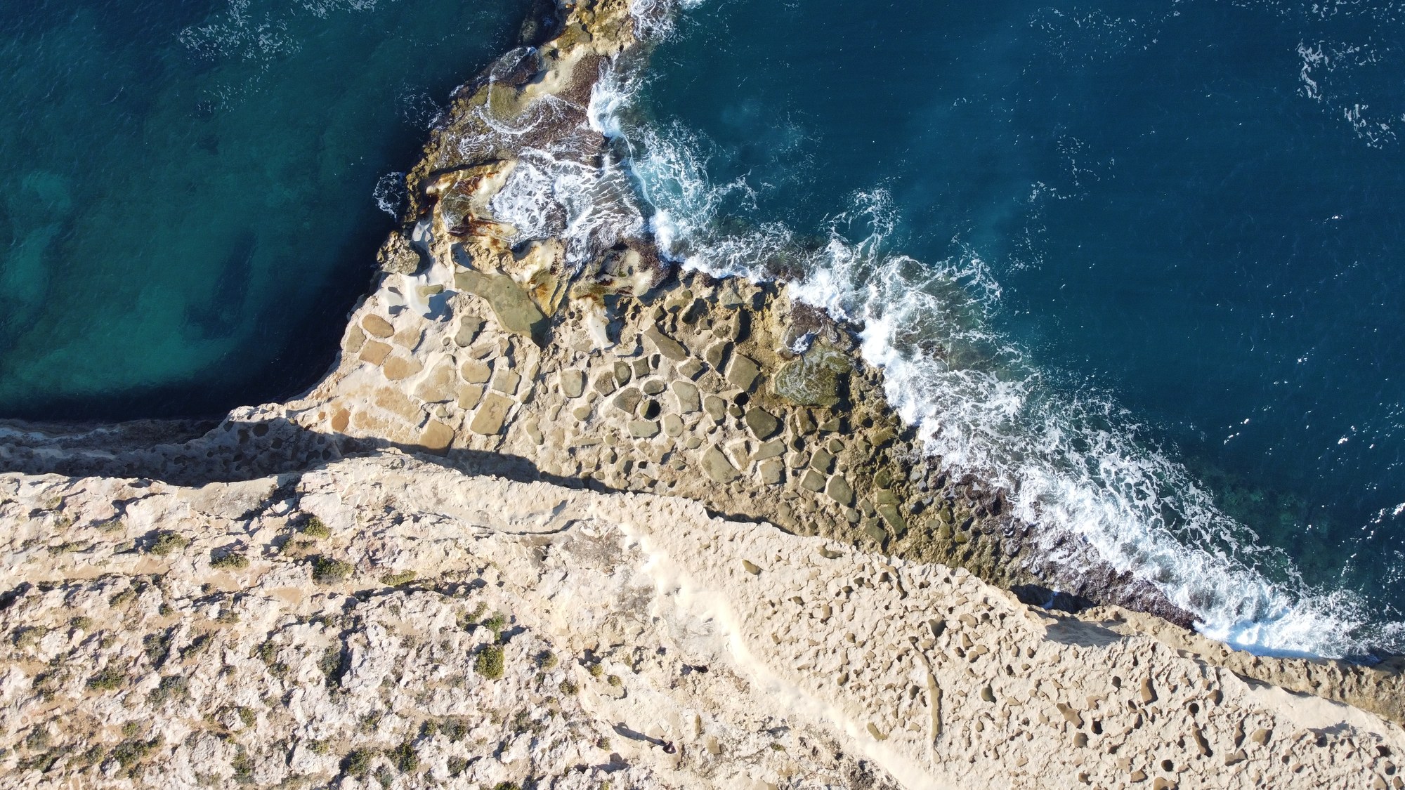 Sea foam tracing the weathered limestone platform below