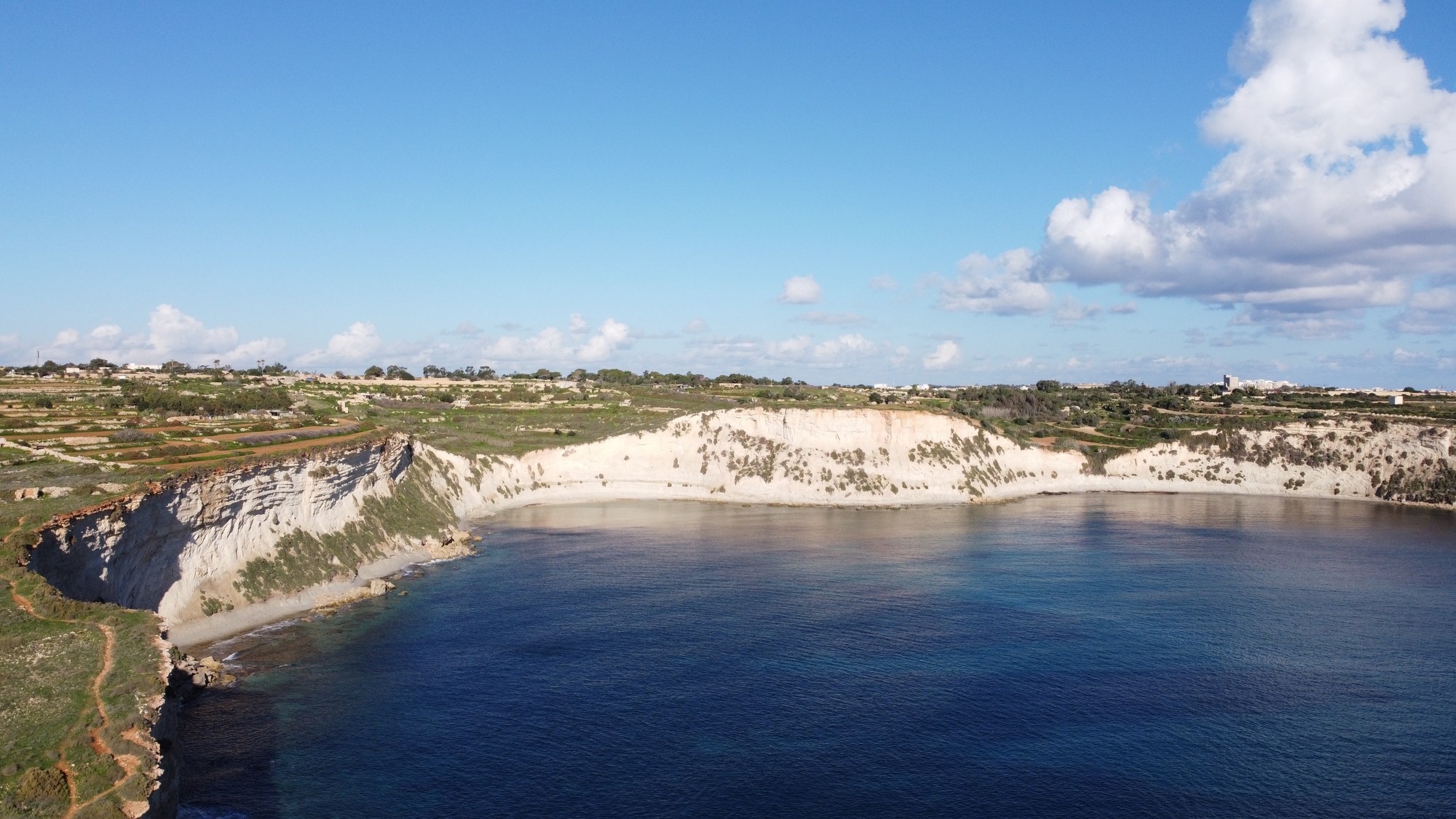 A curved bay enclosed by Malta's white coastal cliffs